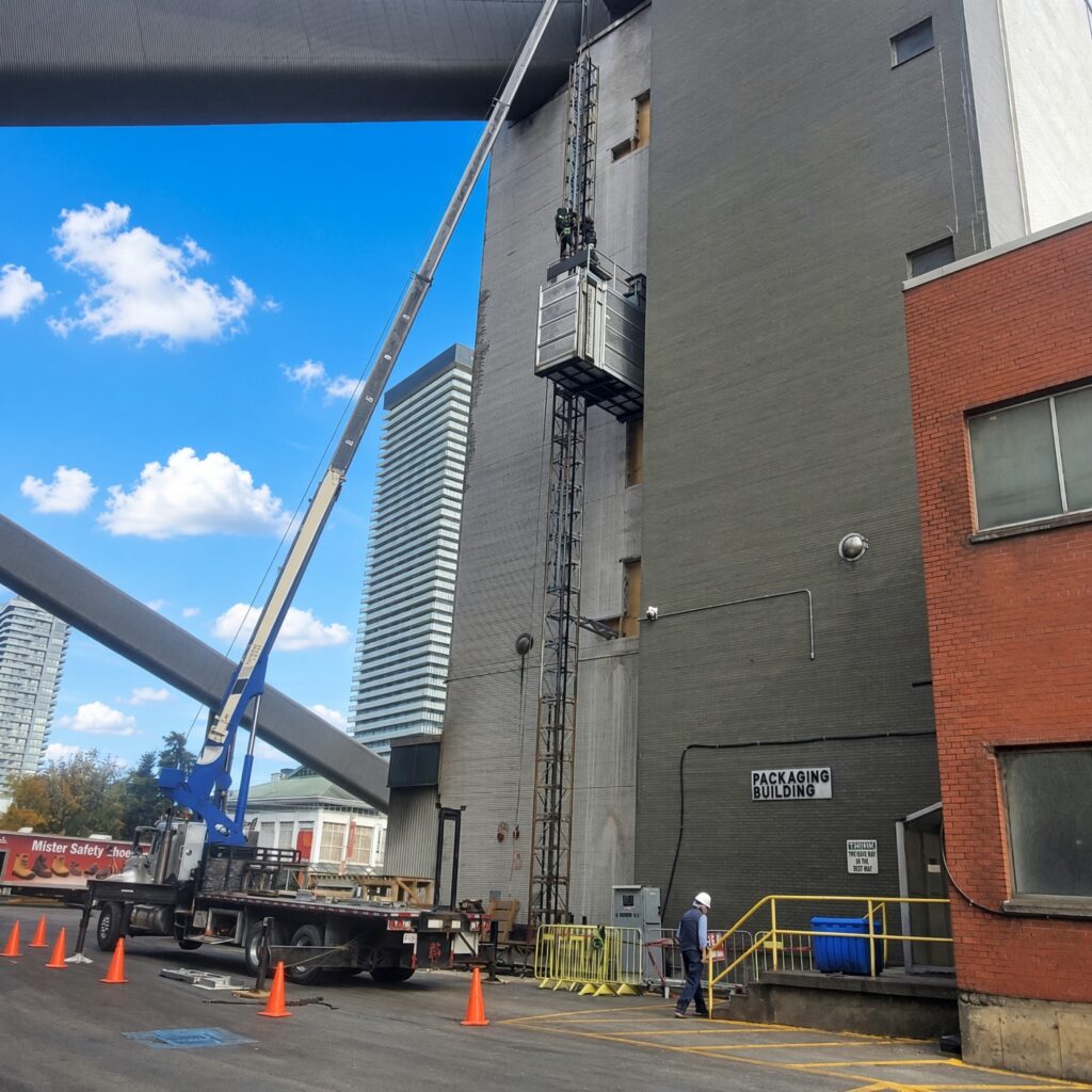 Mobile boom crane truck installing construction hoist mast on industrial facility in Toronto and Burlington, Ontario