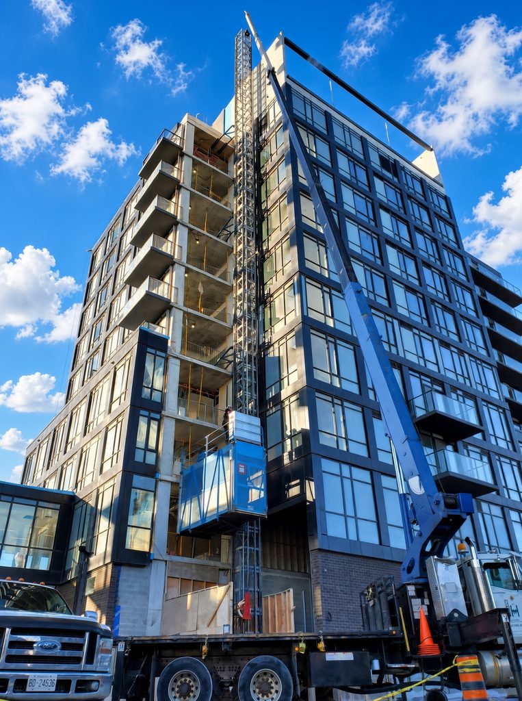 High-rise construction hoist and mobile crane setup on commercial site in Toronto and Burlington, Ontario